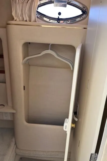 Slide: The Image of 2001 Sea Ray 290 Sundancer cabin closet with hanger and porthole window. - 12