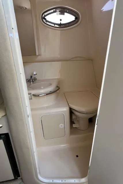 Slide: The Image of 2001 Sea Ray 290 Sundancer bathroom with sink, toilet, and porthole window. - 14