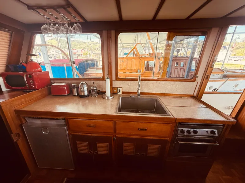 Slide: The Image of 1980 C & L Sea Ranger kitchen with sink, stove, and appliances, featuring large windows. - 16