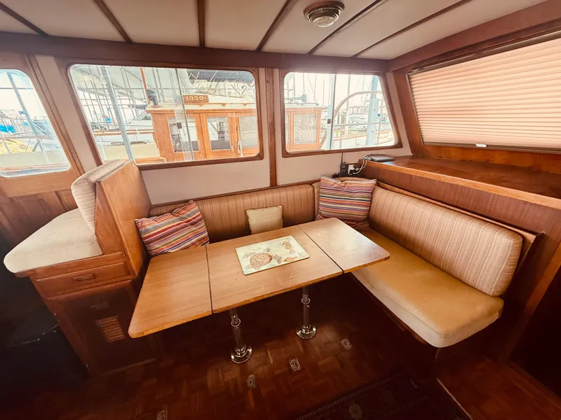 Slide: The Image of 1980 C & L Sea Ranger interior with cozy dining area and striped cushions. - 18