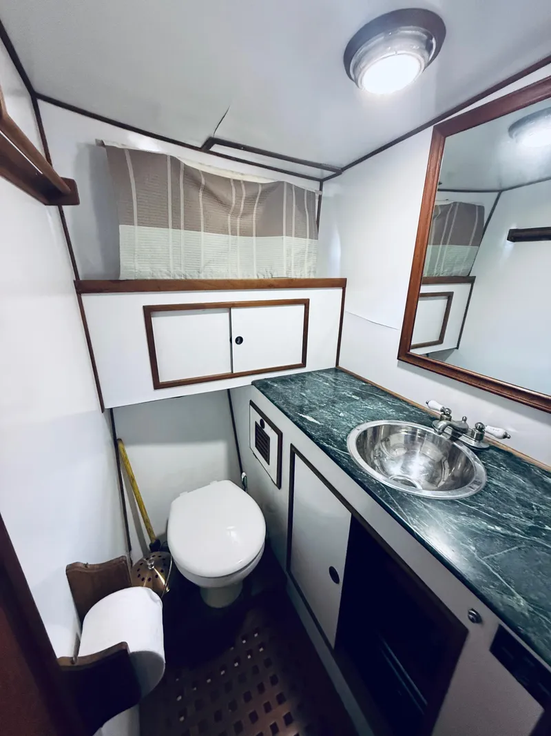 Slide: The Image of 1980 C & L Sea Ranger yacht bathroom with sink, toilet, and storage cabinets. - 36