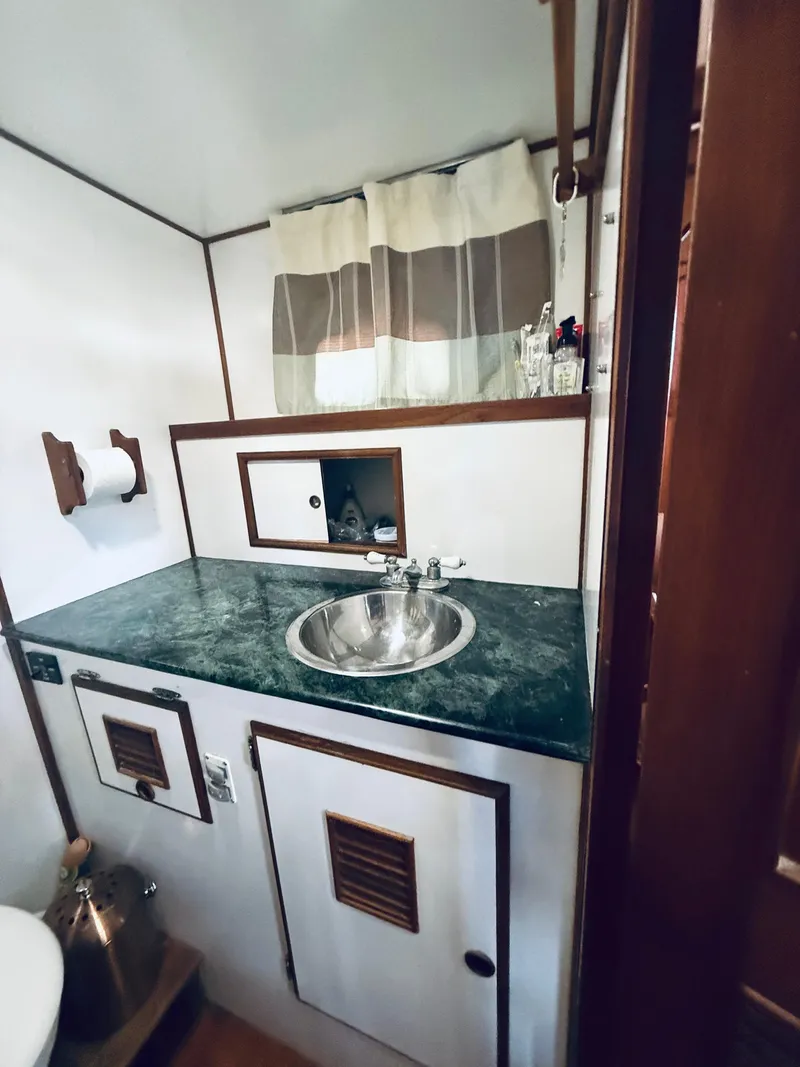 Slide: The Image of 1980 C & L Sea Ranger bathroom with sink, green countertop, and storage cabinets. - 38