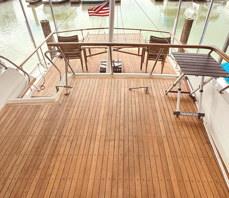 Slide: The Image of 1980 C & L Sea Ranger yacht deck with wooden flooring and chairs, docked near water. - 7