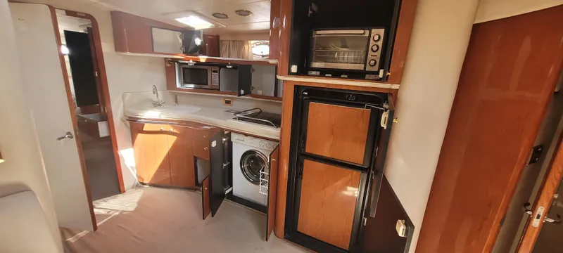 Slide: The Image of Interior of 1998 Sea Ray 450 Sundancer yacht with kitchen appliances and wooden cabinetry. - 18