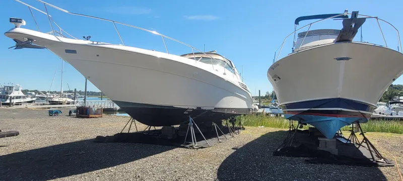 Slide: The Image of 1998 Sea Ray 450 Sundancer yacht on dry dock beside another boat under clear blue sky. - 2