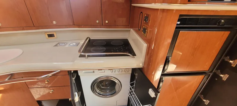 Slide: The Image of 1998 Sea Ray 450 Sundancer kitchen with stove, fridge, and washer. - 22