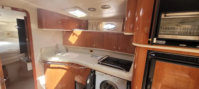 Slide: The Image of Interior of 1998 Sea Ray 450 Sundancer yacht with kitchen amenities and wood cabinetry. - 24
