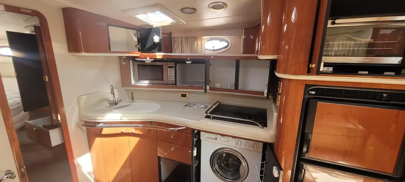 Slide: The Image of 1998 Sea Ray 450 Sundancer yacht kitchen with wood cabinetry, appliances, and washer. - 25