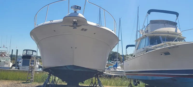 Slide: The Image of 1998 Sea Ray 450 Sundancer yacht on dry dock, alongside another boat, under clear blue sky. - 3