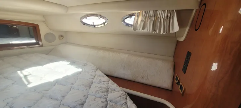 Slide: The Image of 1998 Sea Ray 450 Sundancer cabin interior with bed, portholes, and wood paneling. - 35