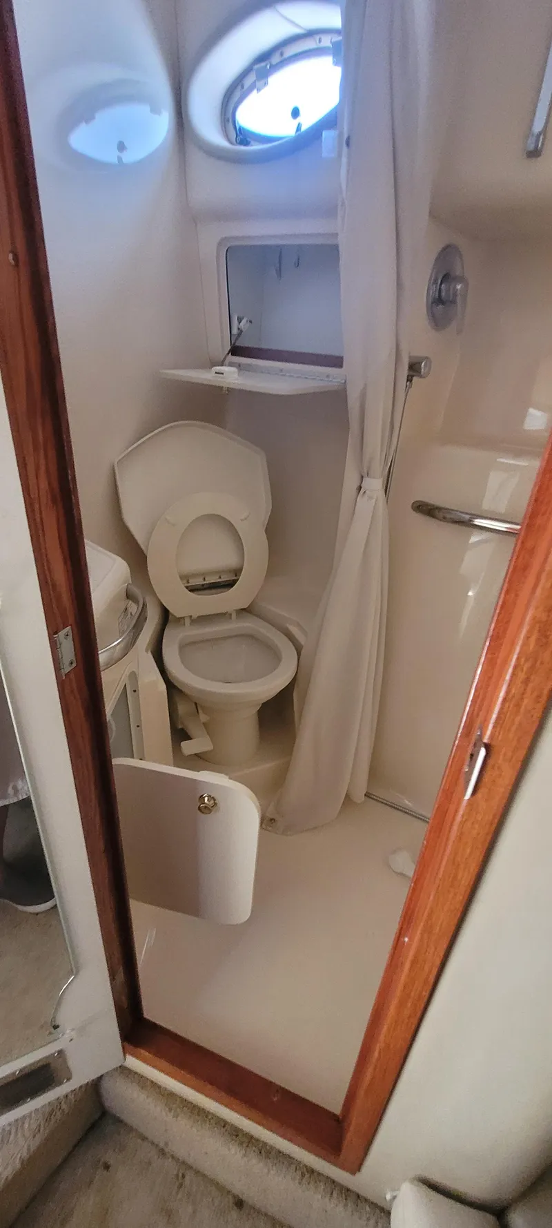 Slide: The Image of 1998 Sea Ray 450 Sundancer bathroom with toilet, shower, and porthole window. - 42