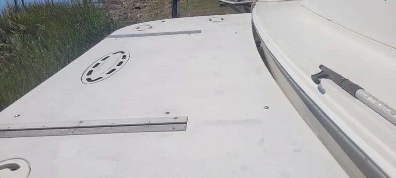 Slide: The Image of 1998 Sea Ray 450 Sundancer deck with hatches and railing, docked near grassy shoreline. - 9