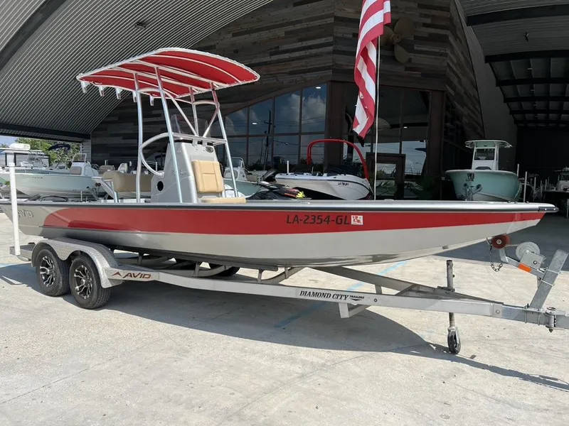 Slide: The Image of 2020 Avid 23 FS Platinum boat on trailer, red and gray design, parked outside. - 3