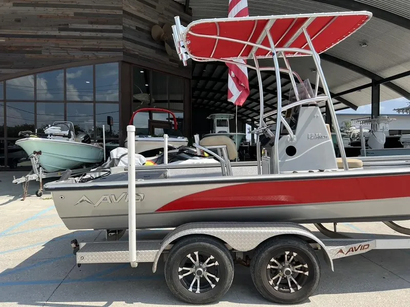 Slide: The Image of 2020 Avid 23 FS Platinum boat with red canopy on trailer, parked outside showroom. - 6