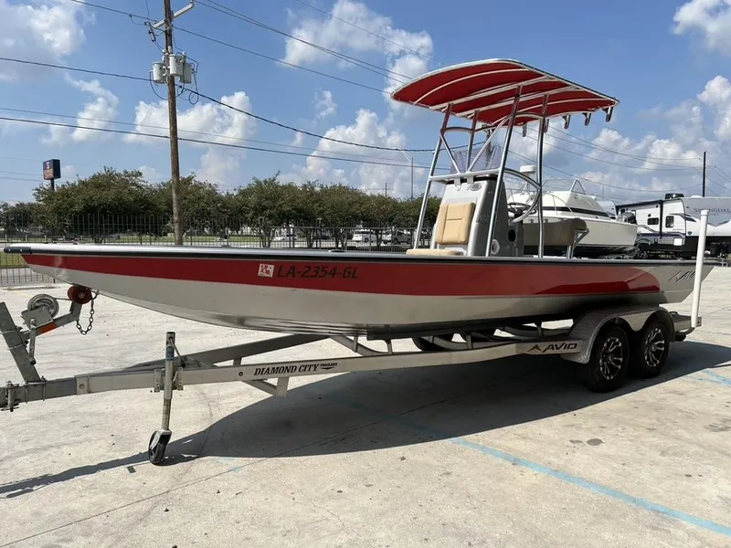 Slide: The Image of 2020 Avid 23 FS Platinum boat on trailer, red and silver design, parked outdoors. - 7