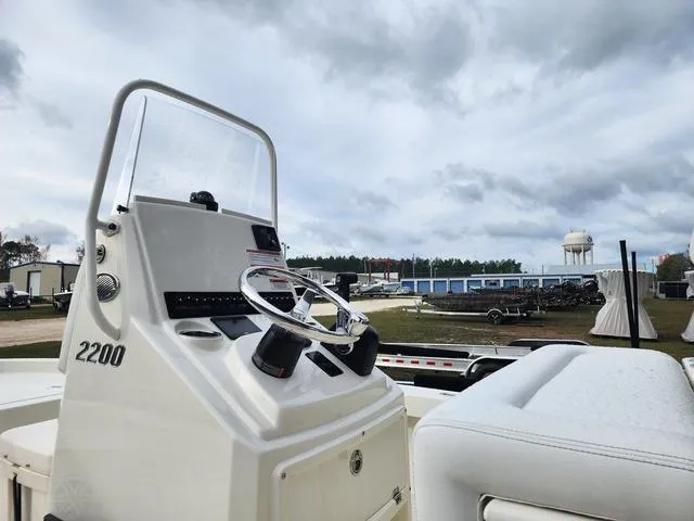 Slide: The Image of 2024 Pathfinder 2200 TRS boat console with steering wheel, outdoors under cloudy sky. - 10