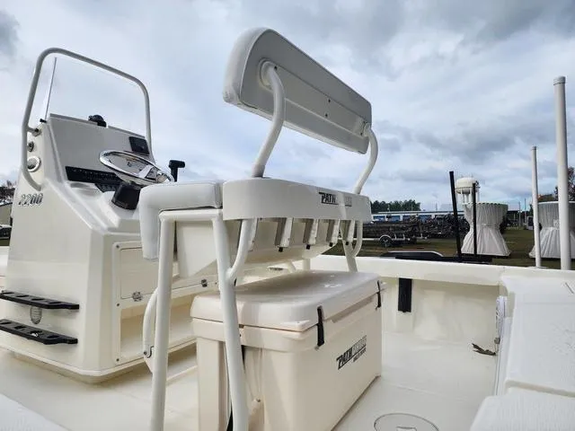 Slide: The Image of 2024 Pathfinder 2200 TRS boat interior with seating and console, under cloudy sky. - 12