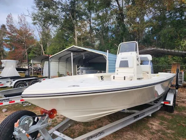 Slide: The Image of 2024 Pathfinder 2200 TRS boat on trailer, parked outdoors near trees and a shed. - 14
