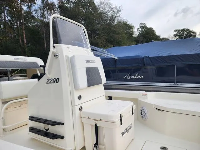 Slide: The Image of 2024 Pathfinder 2200 TRS boat with console and seating, docked near covered Avalon boat. - 20