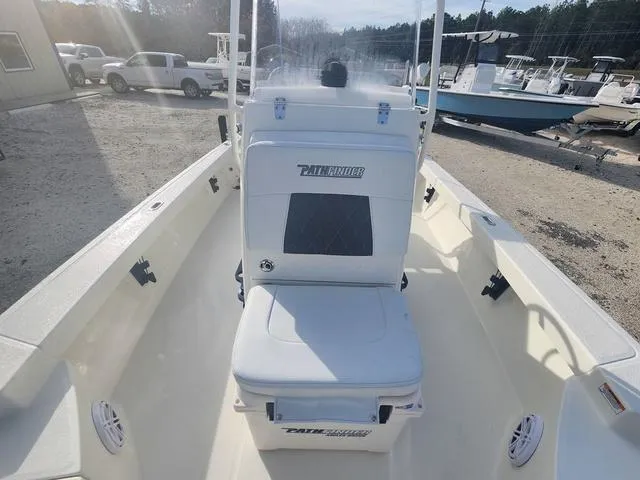 Slide: The Image of 2024 Pathfinder 2200 TRS boat interior with seating and console, parked outdoors. - 32