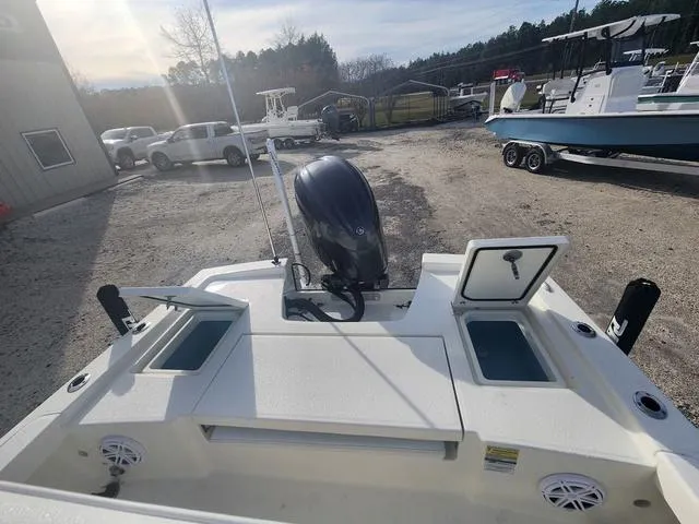 Slide: The Image of 2024 Pathfinder 2200 TRS boat with open storage compartments and outboard motor in a sunny lot. - 45