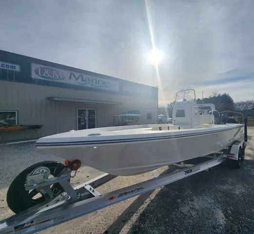 Slide: The Image of 2024 Pathfinder 2200 TRS boat on trailer outside L&M Marine under bright sun. - 6