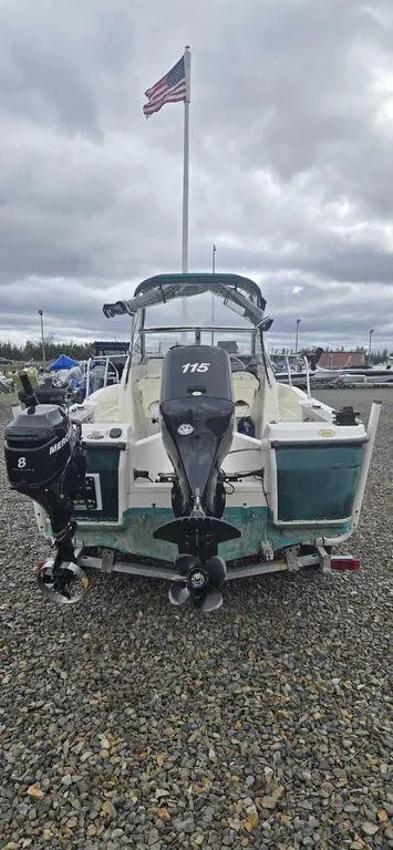 Slide: The Image of 2006 Bayliner Trophy 1802 WA boat with outboard motor, parked on gravel, American flag in background. - 1