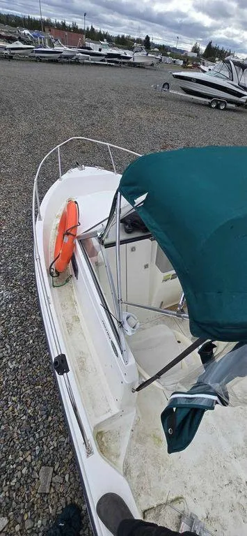 Slide: The Image of 2006 Bayliner Trophy 1802 WA boat with green canopy and life preserver, parked on gravel. - 3
