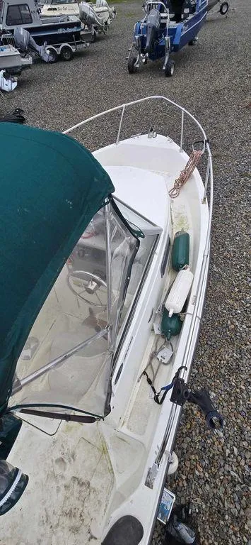Slide: The Image of 2006 Bayliner Trophy 1802 WA boat with green canopy, docked on gravel. - 9