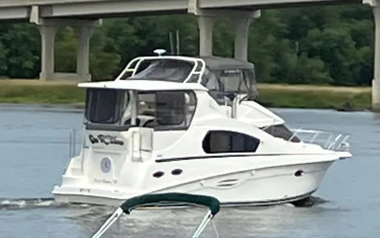 Slide: The Image of 2005 Silverton 35 Motor Yacht cruising on a river near a bridge. - 2