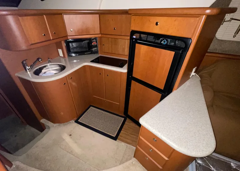 Slide: The Image of 2005 Silverton 35 Motor Yacht kitchen with wood cabinetry, sink, microwave, and fridge. - 30