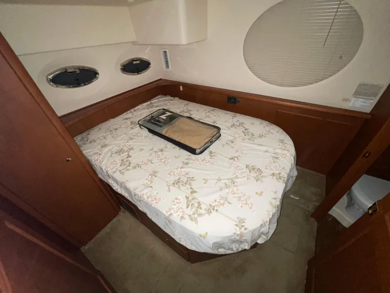 Slide: The Image of 2005 Silverton 35 Motor Yacht bedroom with floral bedding and porthole windows. - 34