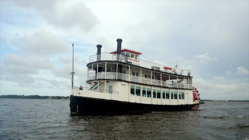 The Image of Vintage 1984 custom paddle wheel boat cruising on a calm river under cloudy skies. - 0