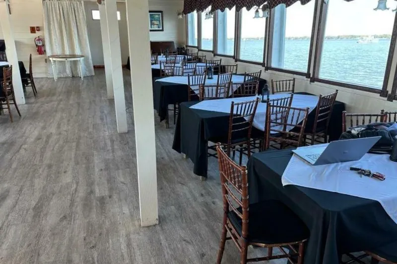 Slide: The Image of Interior of a 1984 custom paddle wheel boat with tables, chairs, and a scenic water view. - 28