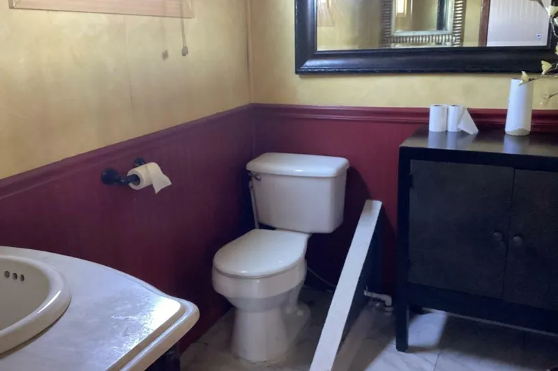 Slide: The Image of Small bathroom with toilet, sink, mirror, and cabinet, featuring red and beige walls. - 32