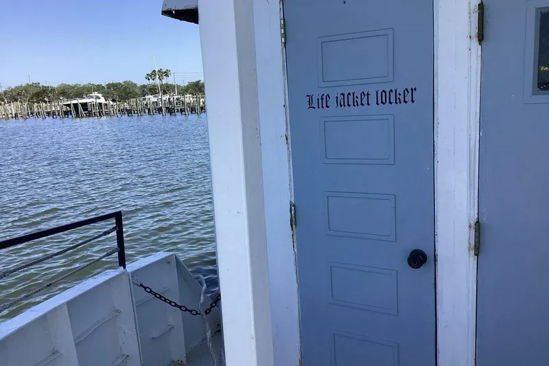 Slide: The Image of Blue life jacket locker door on a 1984 Custom Paddle Wheel boat by the water. - 34