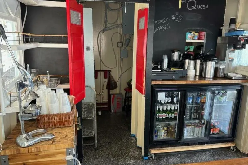 Slide: The Image of Cozy cafe interior with beverage station, red doors, and stocked drink fridge. Custom Paddle Wheel, 1984. - 56