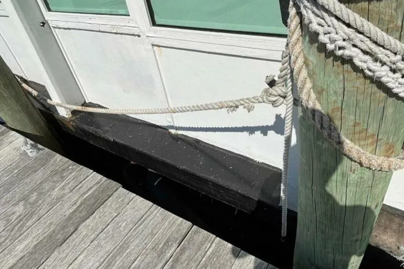 Slide: The Image of Docked custom paddle wheel boat from 1984, secured with ropes to a wooden post. - 67