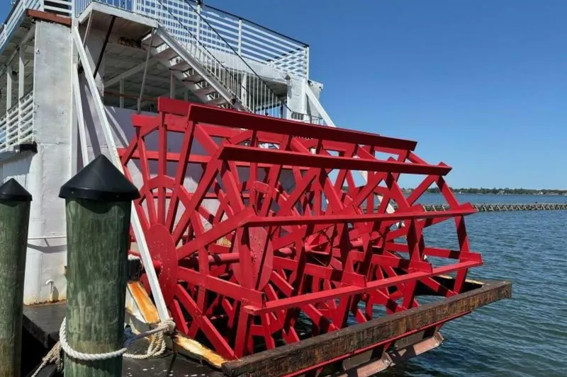 Slide: The Image of Red paddle wheel on a custom 1984 riverboat docked by the water. - 7