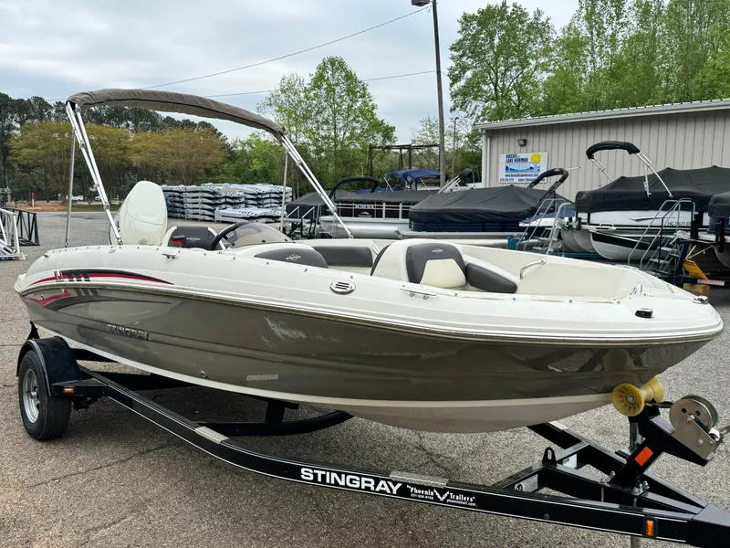 Slide: The Image of 2019 Stingray 182 SC boat on trailer, parked outdoors with trees and buildings in background. - 3