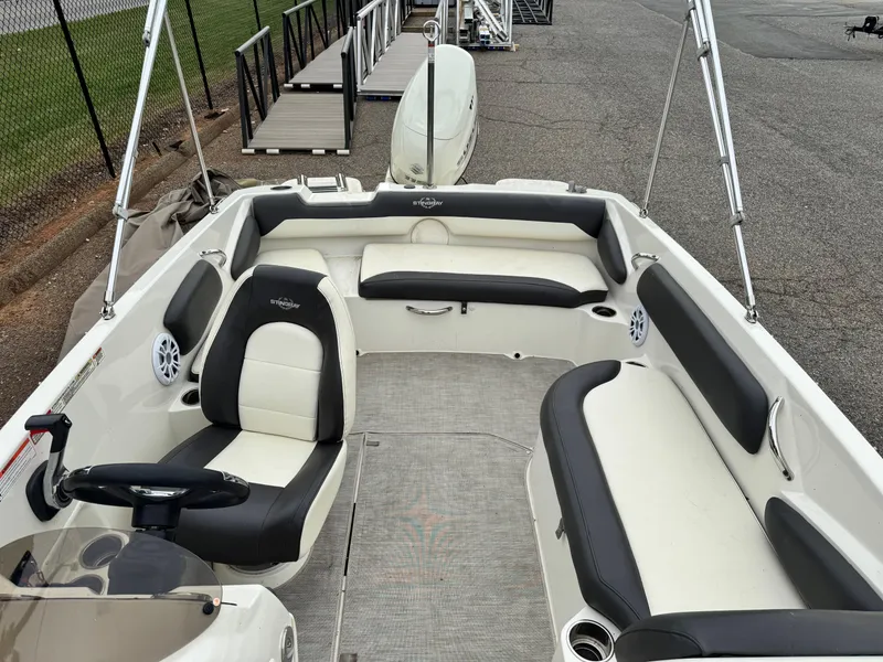 Slide: The Image of 2019 Stingray 182 SC boat interior with seating and steering wheel, docked at marina. - 6