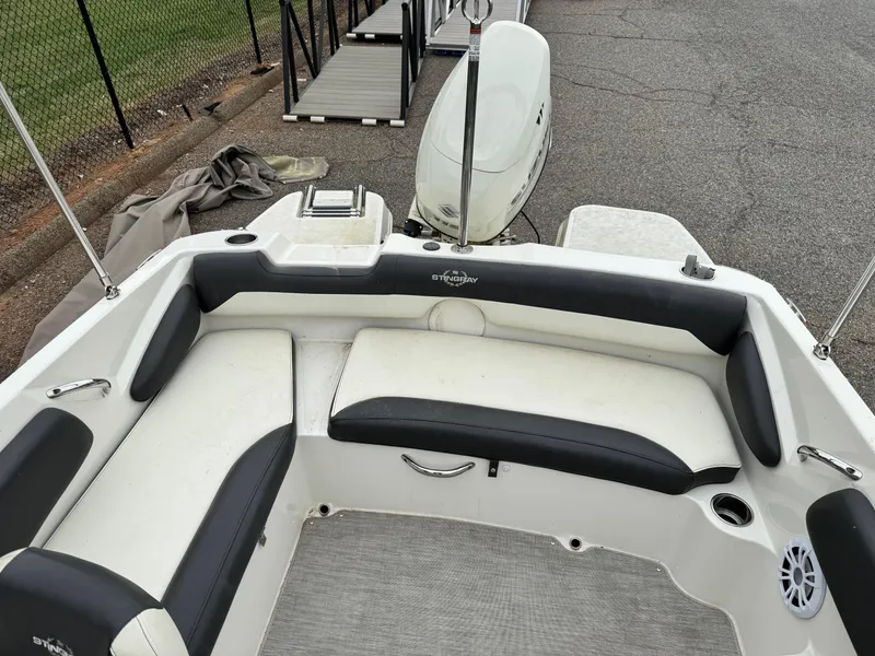 Slide: The Image of 2019 Stingray 182 SC boat interior with white and black seating, docked by a pier. - 7