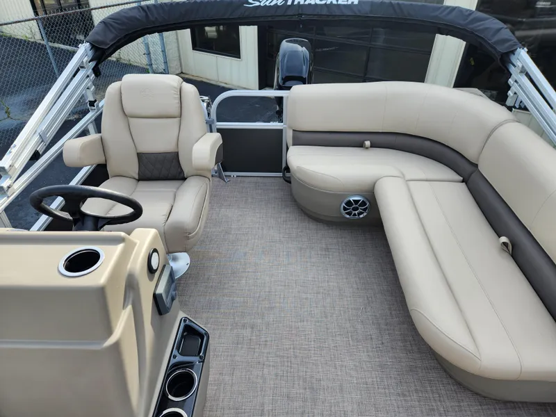 Slide: The Image of 2025 Sun Tracker Party Barge 16 DLX interior with beige seating and steering console. - 10