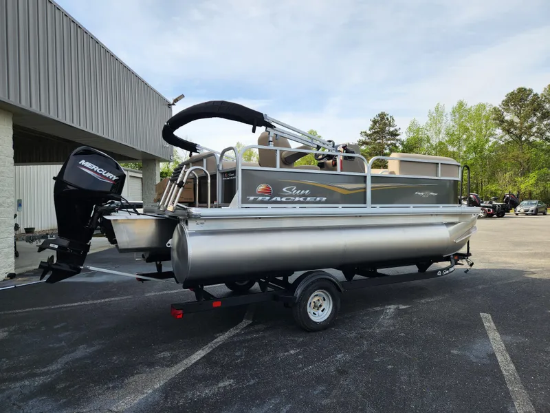 Slide: The Image of 2025 Sun Tracker Party Barge 16 DLX pontoon boat on trailer in parking lot. - 2