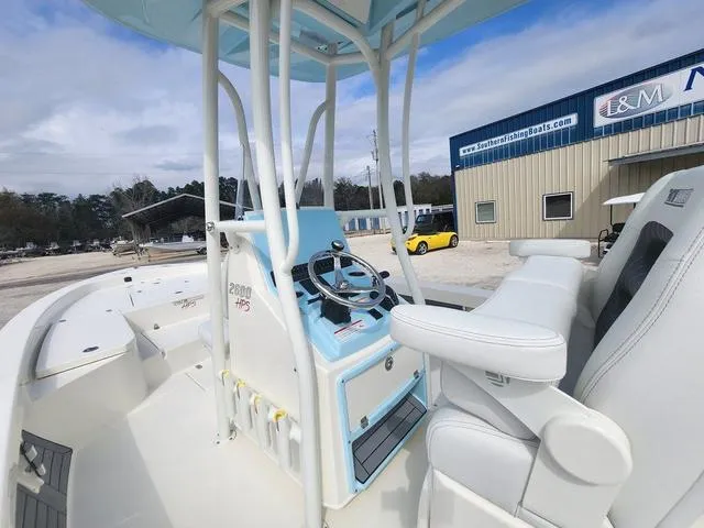 Slide: The Image of 2024 Pathfinder 2600 HPS boat interior with steering console and seating, parked near a building. - 18