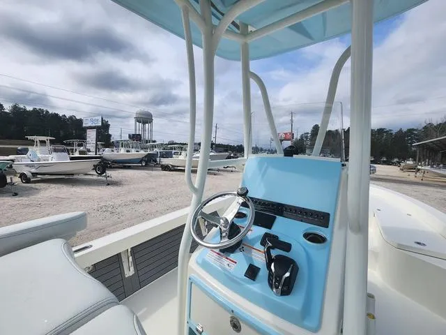Slide: The Image of 2024 Pathfinder 2600 HPS boat console with steering wheel, parked in a marina. - 9