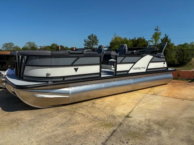 The Image of 2025 Trifecta 23 RF SS pontoon boat on concrete, sunny day, side view. - 1