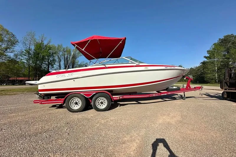 Slide: The Image of 1997 Cobalt 220 boat with red canopy on a trailer, parked outdoors. - 1