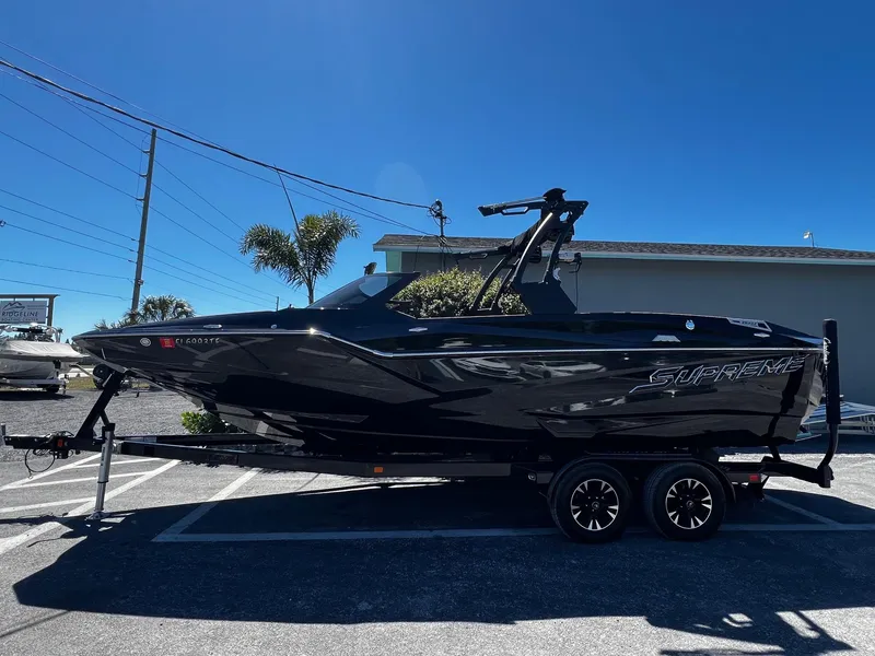 Slide: The Image of 2019 Supreme ZS232 boat on trailer, sleek black design, parked outdoors under clear blue sky. - 5