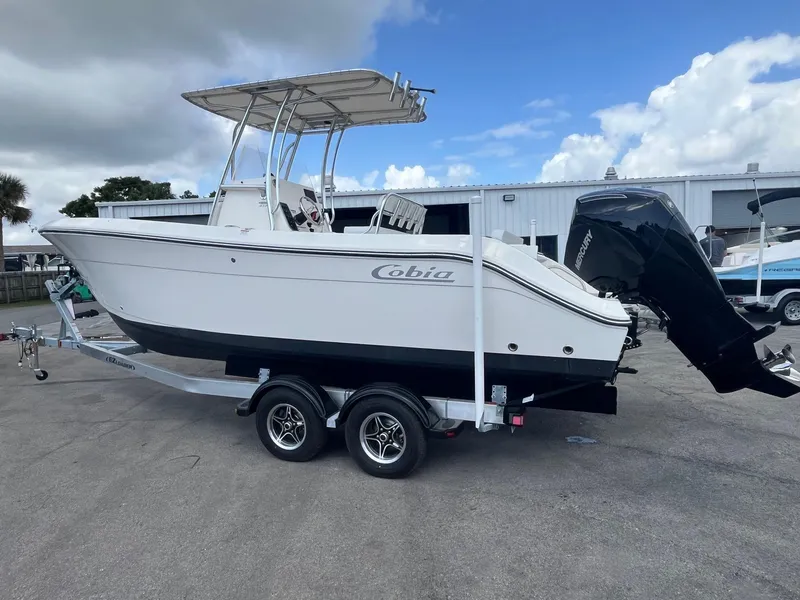Slide: The Image of 2022 Cobia 237 Center Console boat on trailer, parked outdoors under cloudy sky. - 1